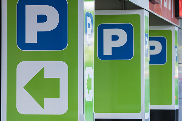 Green parking signs with a white P and a left arrow at a car park entrance