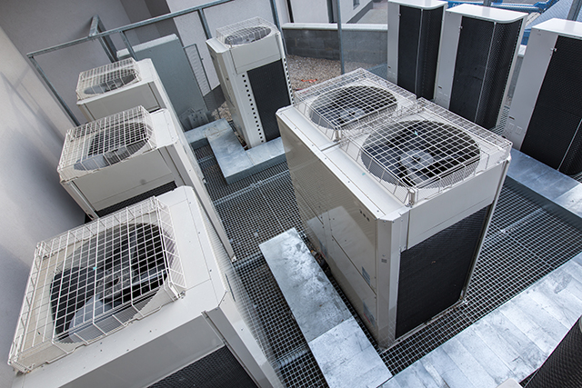 Several outdoor condenser units on a grated rooftop plant deck